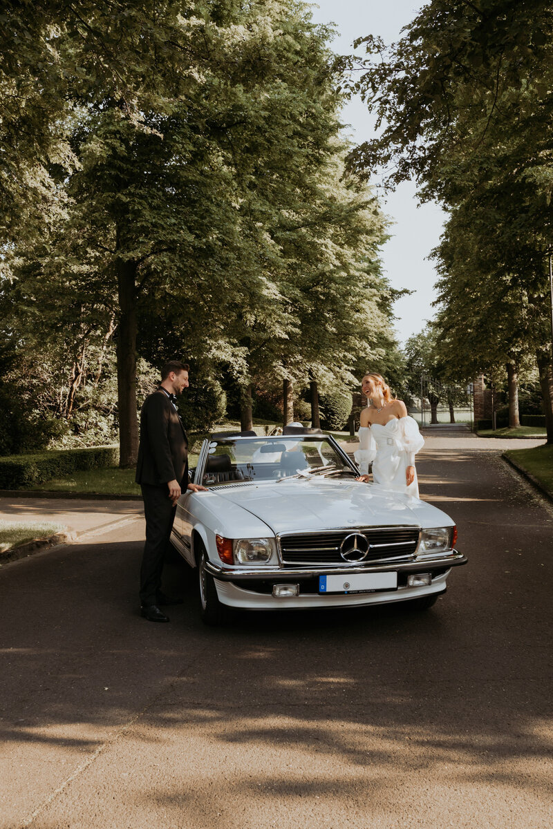 Hochzeitspaar stehend am Auto am Gut Lärchenhof