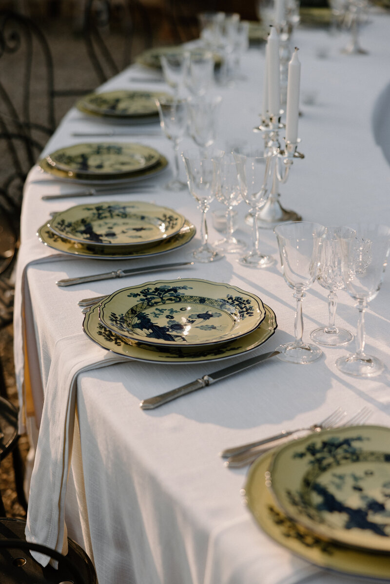 A circular wedding reception table with intricately decorated plates on it 