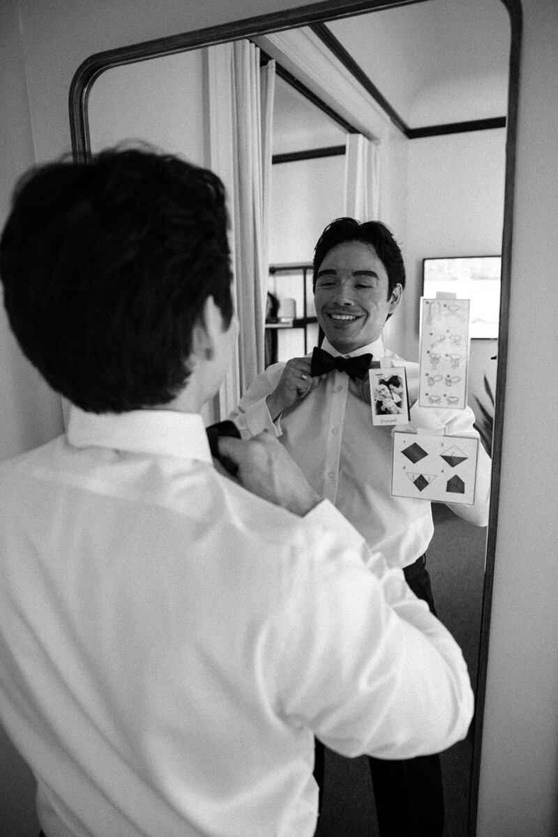 groom getting ready in front a mirror and fixing his bowtie