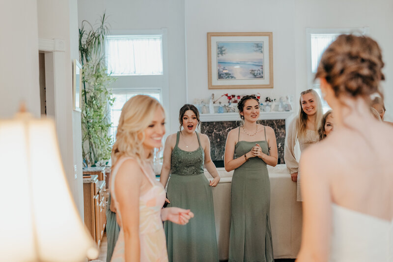 bride revealing dress to bridesmaids