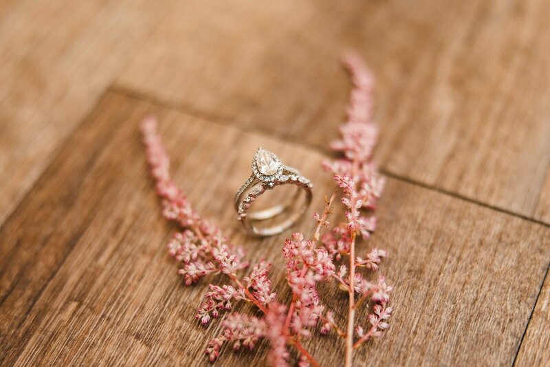 Bride's rings with light pink flowers on wood background.