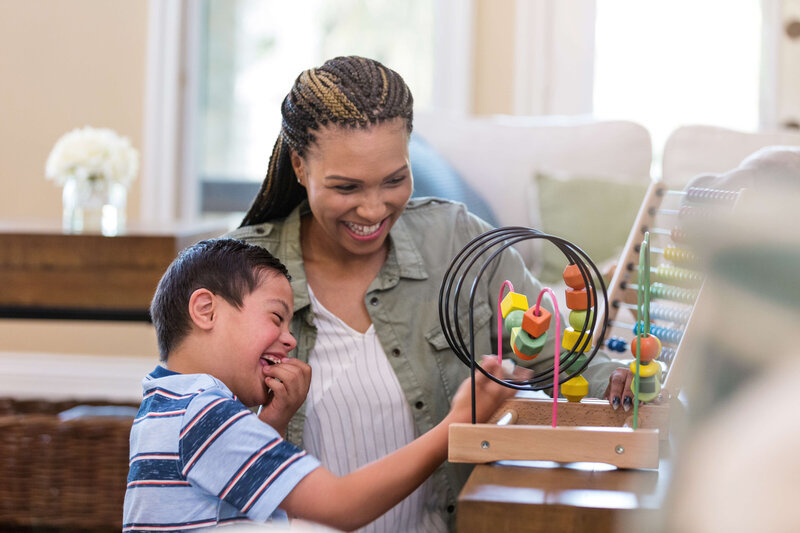 teacher assisting child with a toy. Kid is laughing