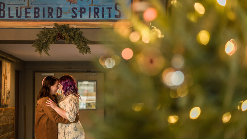 Same-sex couple sharing a romantic moment and drinks at Blue Bird Distilling in Phoenixville during their unique engagement session.