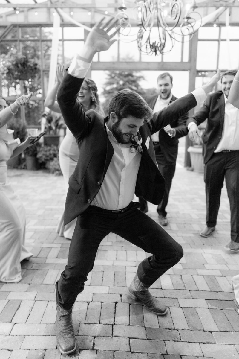 millennial groom dancing with hands up
