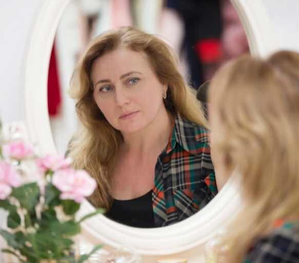 A photo t a woman looking in the mirror