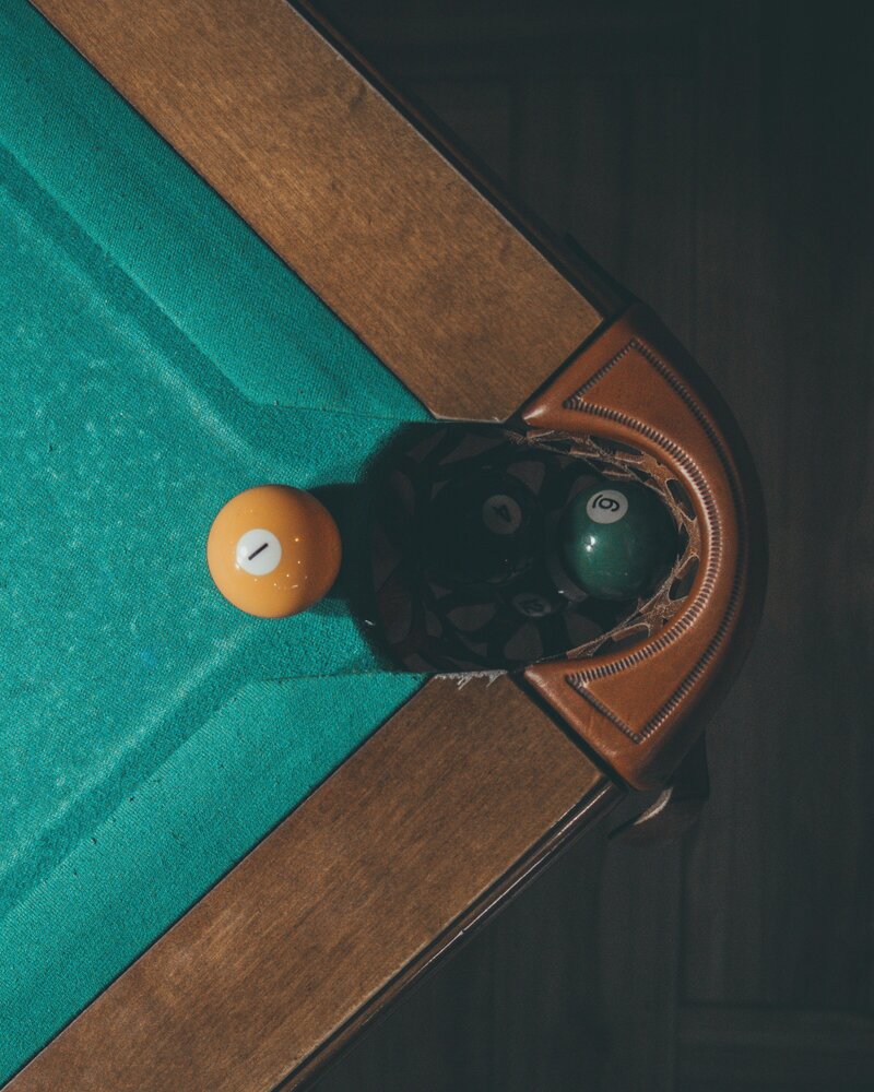 Close-up of a billiards or pool table corner pocket with a yellow ball nearby.