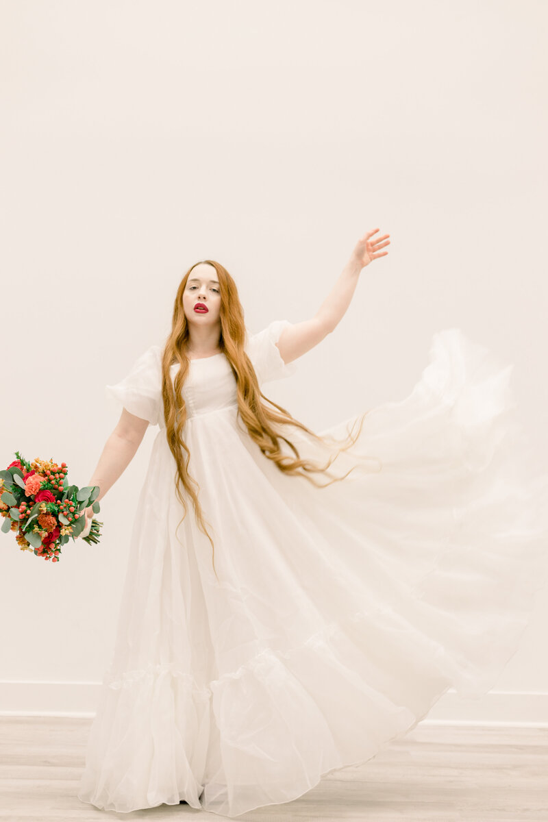 birde playing with her white dress and holding flowers