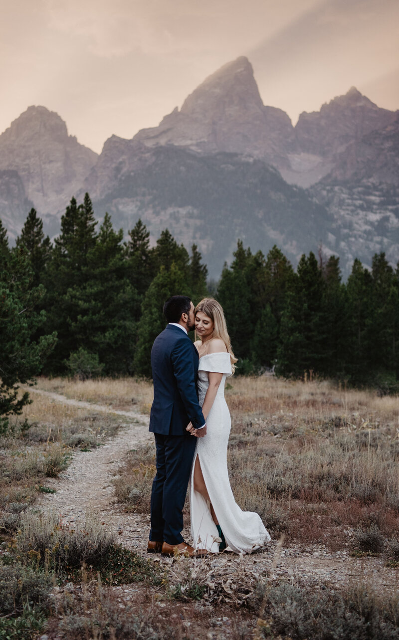 jackson hole wedding portraits with bride adn groom holding hands and whispering into each others ears for a wyoming elopement in the fall