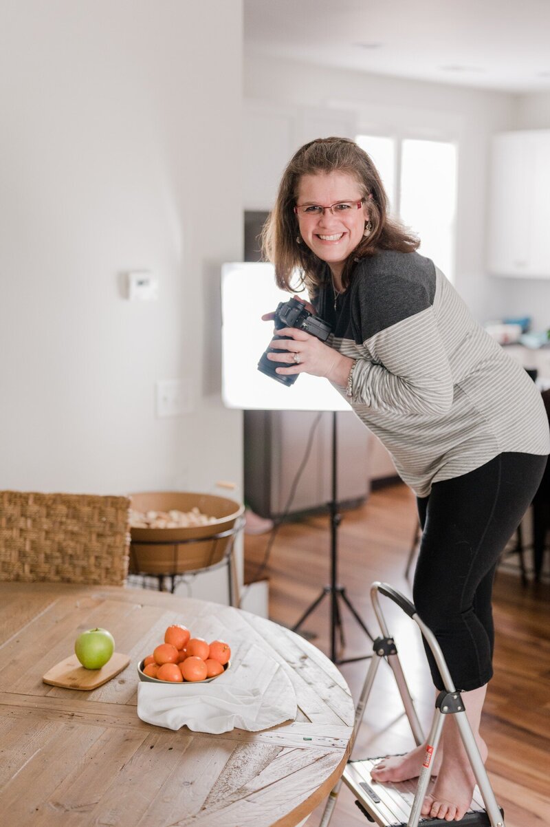 Image of Amanda, lead brand photographer, at work photographing food displays on a kitchen table