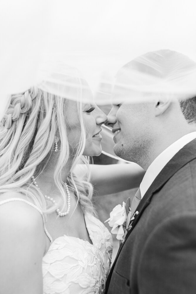 black and white portrait of bride and groom about to kiss