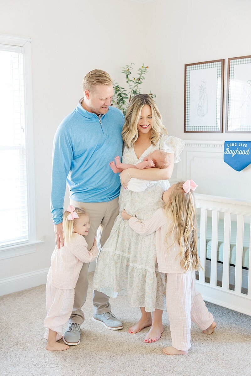 toddler sisters excited for newborn baby brother in nursery family photo