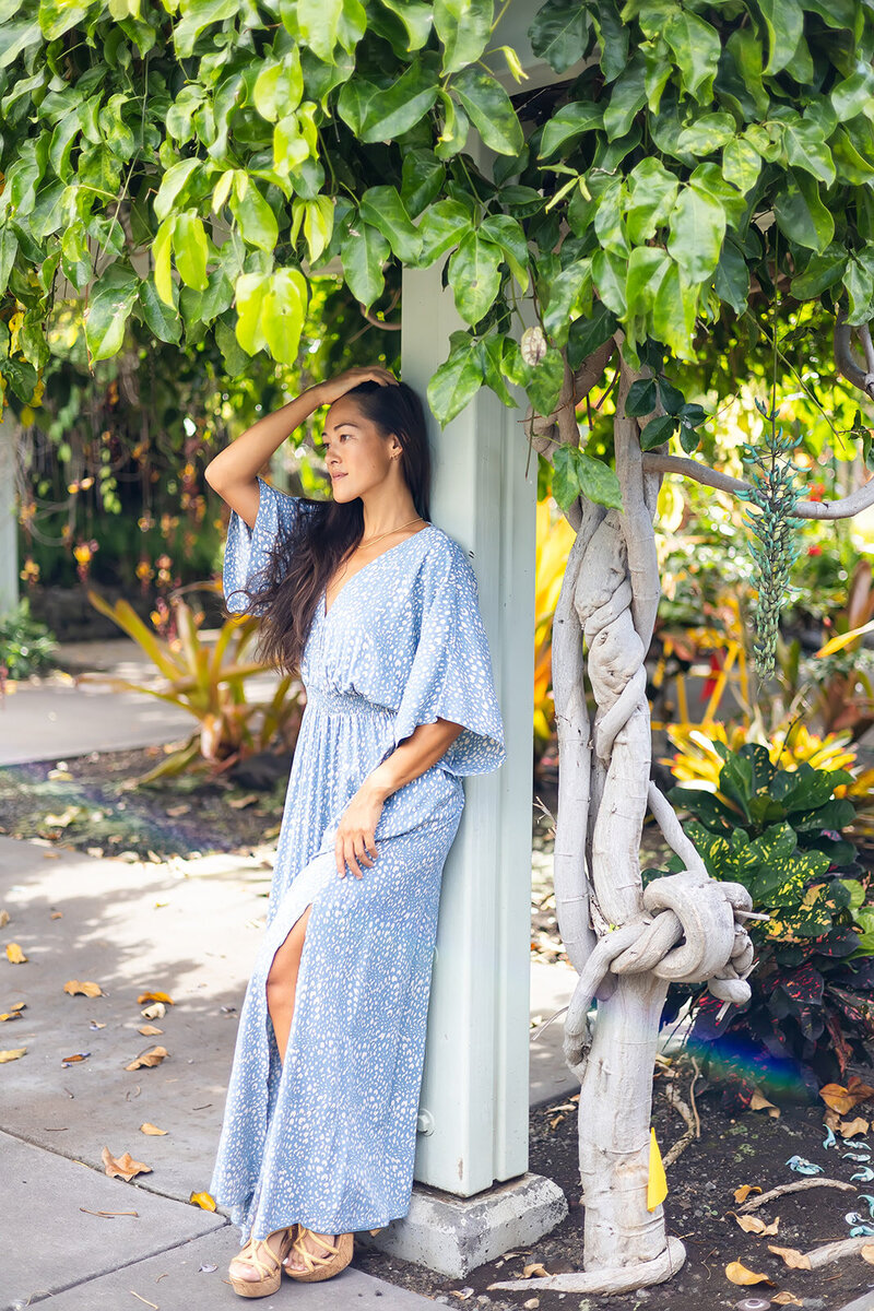 boutique fashion model in blue dress posing in a tropical garden