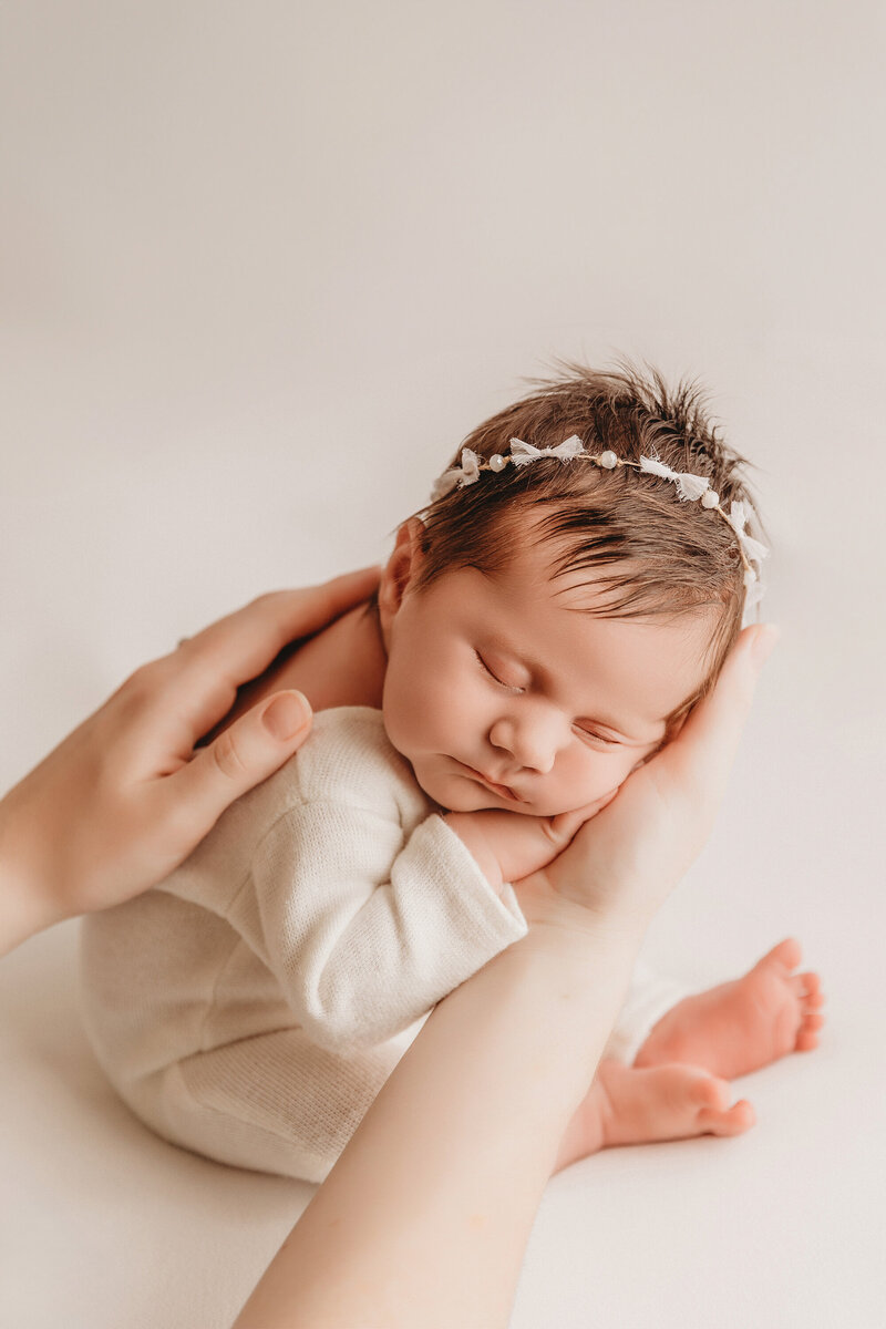 newborn baby portraits in phoenix newborn studio in white outfit on moms hands
