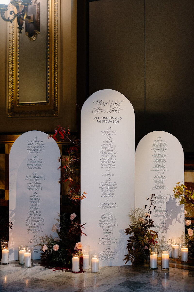 Three ivory arches with calligraphy seating chart display for luxury wedding