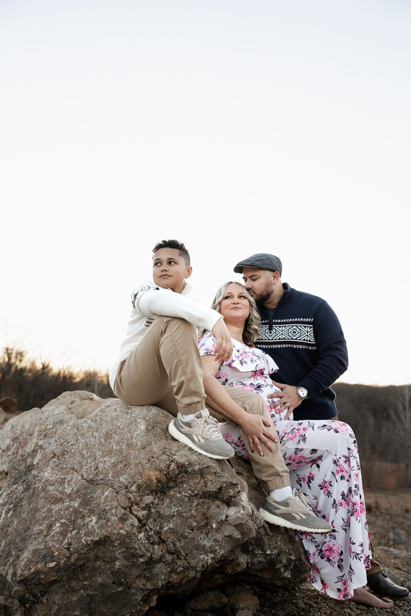 Expecting family sitting on a large rock at sunset in Farmington, Missouri. 