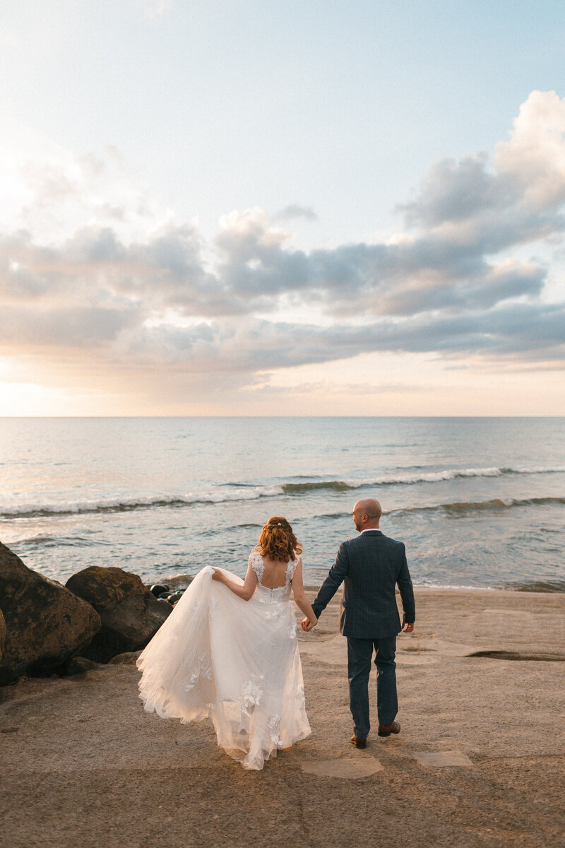 Couple walk towards the sea at the beach at sunset in North Devon 