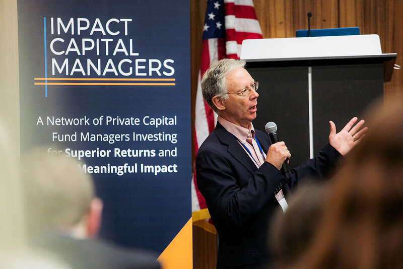 A man with a microphone talking at a conference