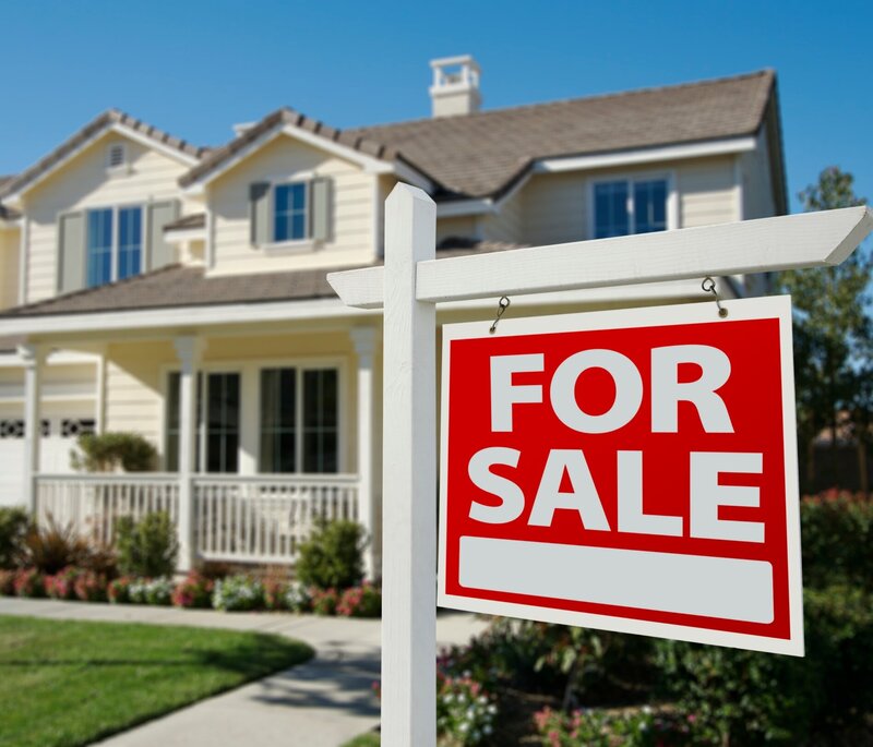 White house in the background with a for sale sign out front