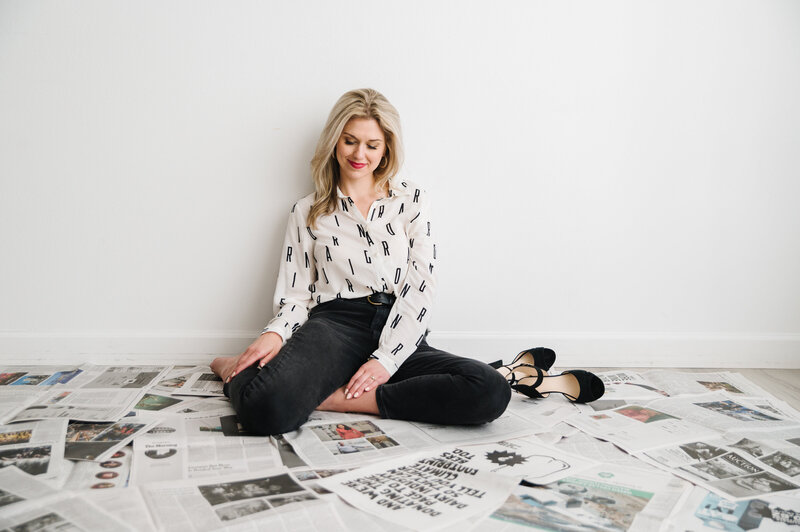 Sarah Klongerbo sitting on a floor covered with newspaper pages