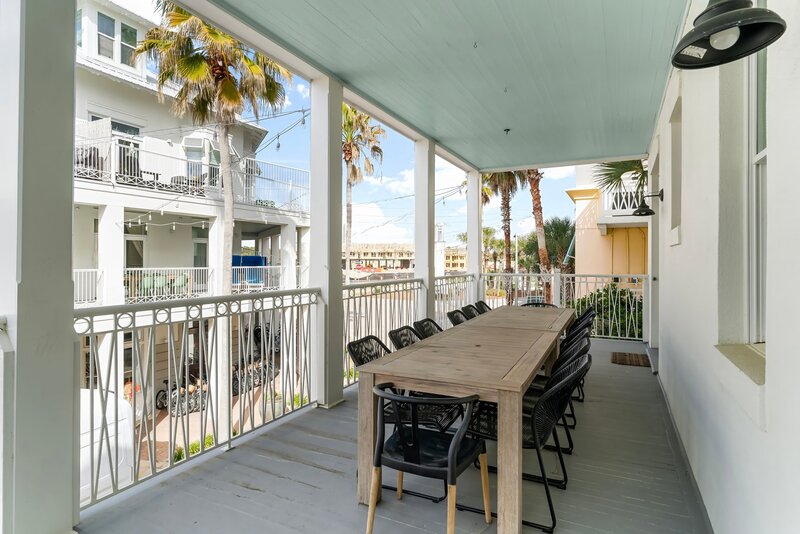 Charming balcony with large dining table and palm-lined views at The Florida House, an ideal spot for gatherings near Panama City Beach and 30A vacation rentals.