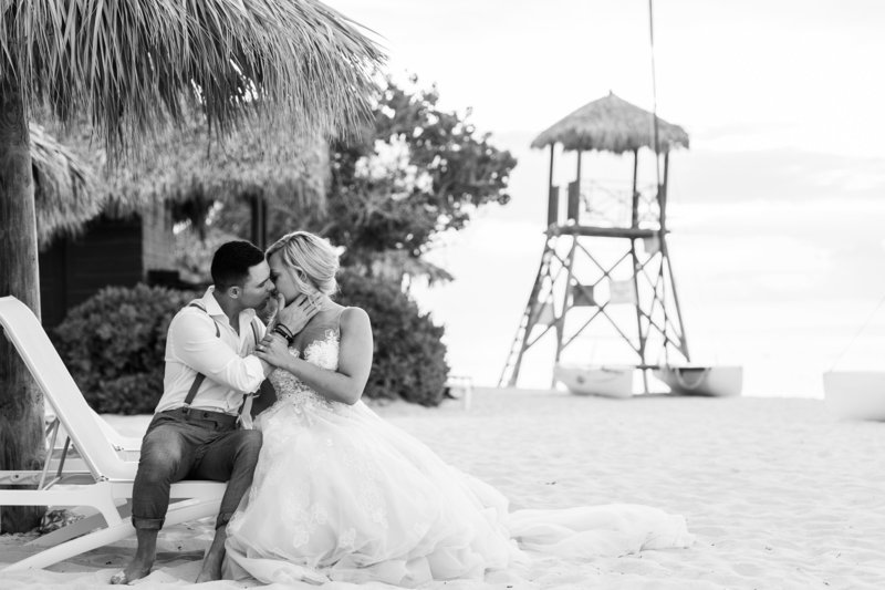 Black and white photo of newlywed couple kissing on the beach