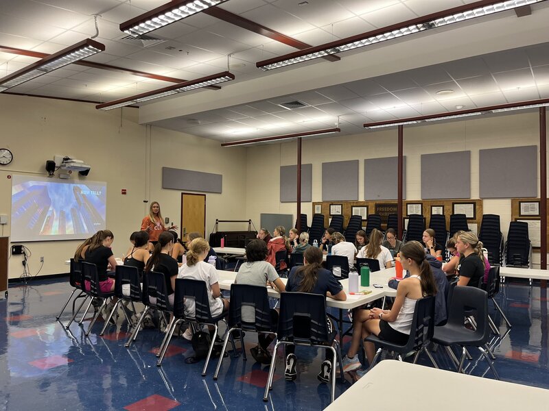 A female speaking in front of high school students