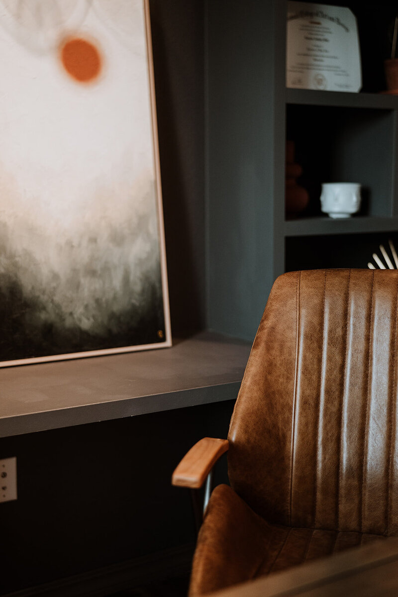 leather office chair with painting on desk behind