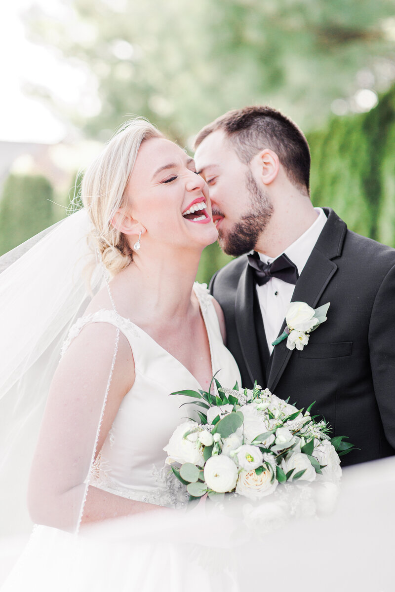 Bride and groom laughing with veil sweeping in front