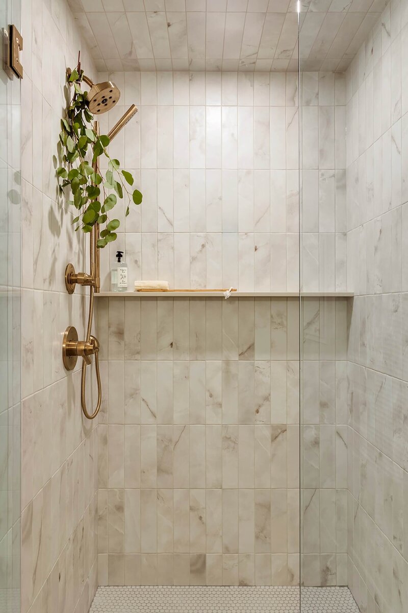 A beautiful shower with neutral tile and gold accents. 