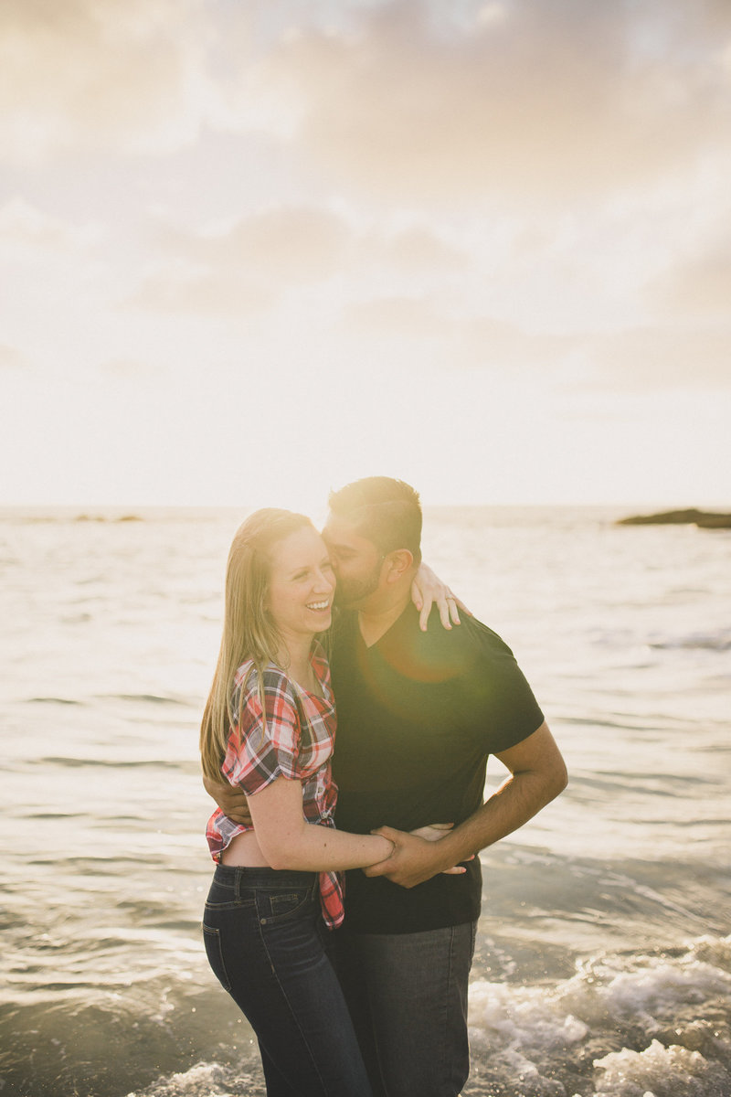 couple play in the waves for engagement portraits in orange county california