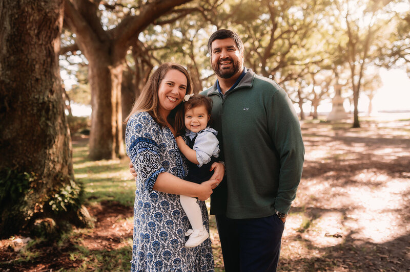 Parents embrace their toddler during Family Photoshoot in White Point Garden in Charleston, South Carolina.