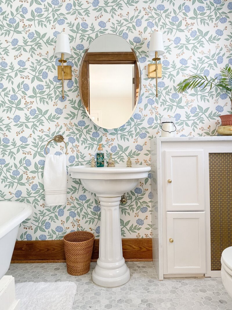 A classic bathroom design featuring a clawfoot tub and a light and dainty wallpaper on the walls.