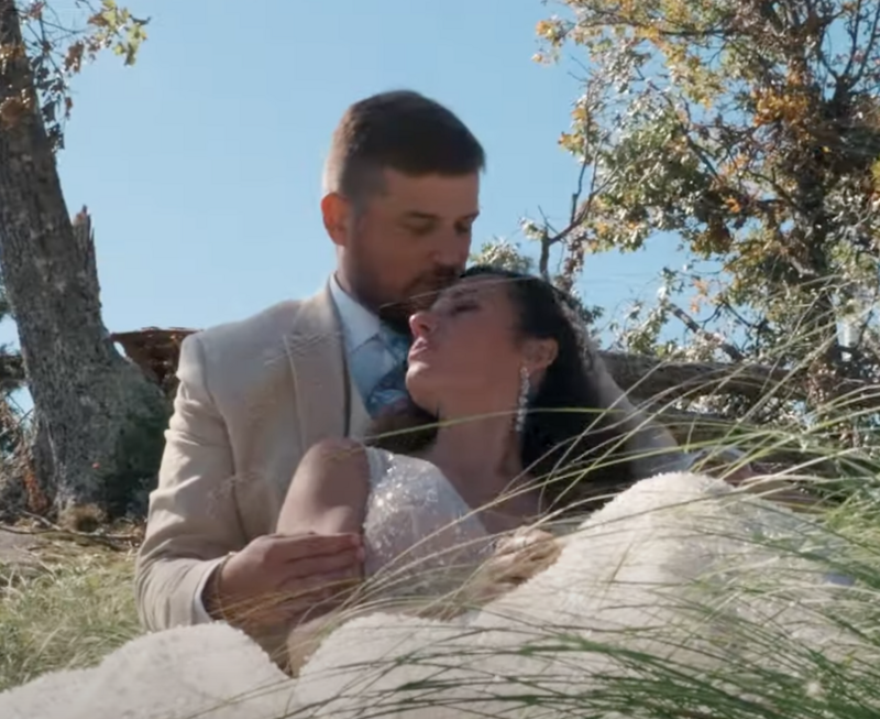 A newlywed couple sitting together as one leans back into the other 