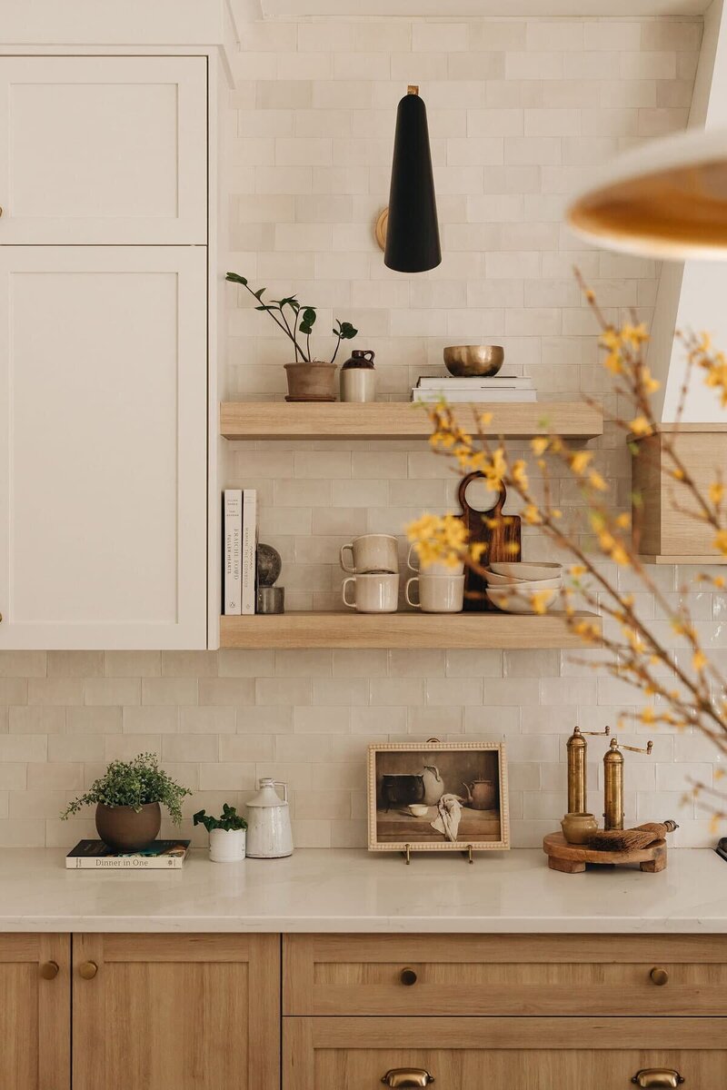 Open kitchen shelving with ceramic mugs, brass accents, and warm neutral tones in a modern Montreal home – by Ingrid Interior Design.