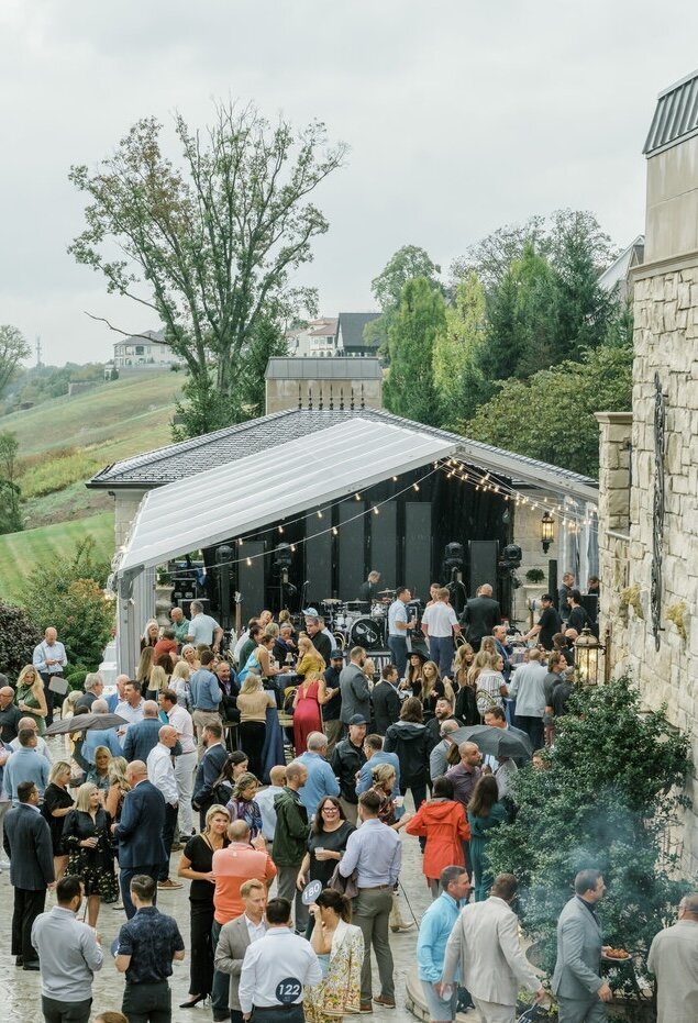 Large crowd gathered under a tent at an outdoor event.
