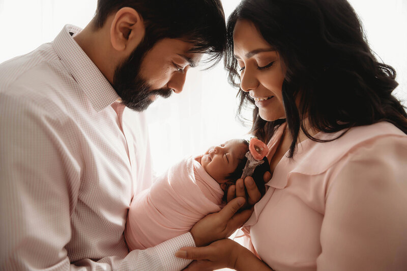 New parents embrace their infant during Newborn Portrait Session in Charleston, SC.