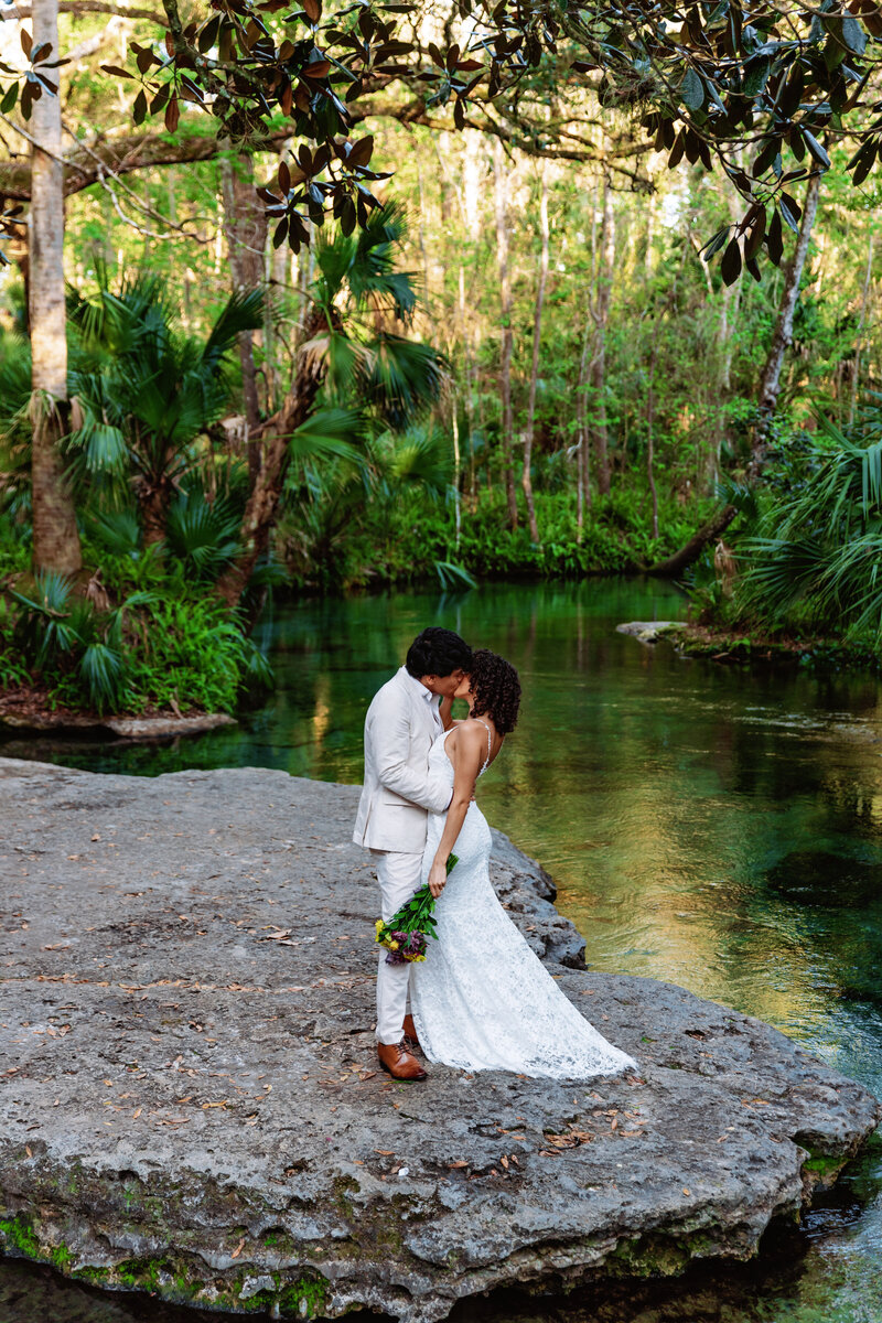 Florida elopement photographer capturing a romantic moment between a couple at a serene, lush location by the water.