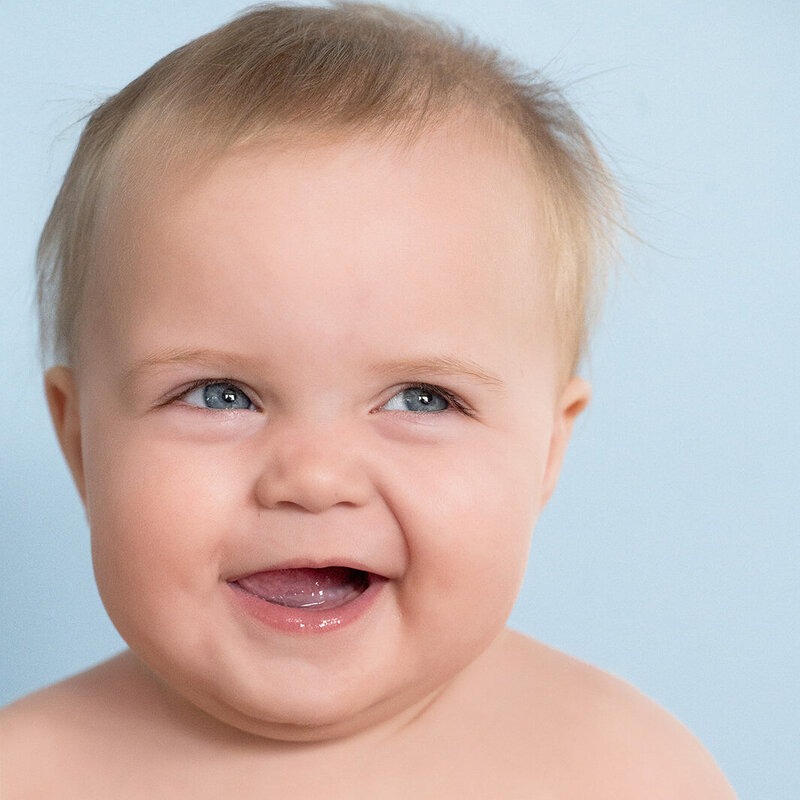 Cute baby smiling during milestone photo session with blue backdrop – Lancaster, PA milestone photographer