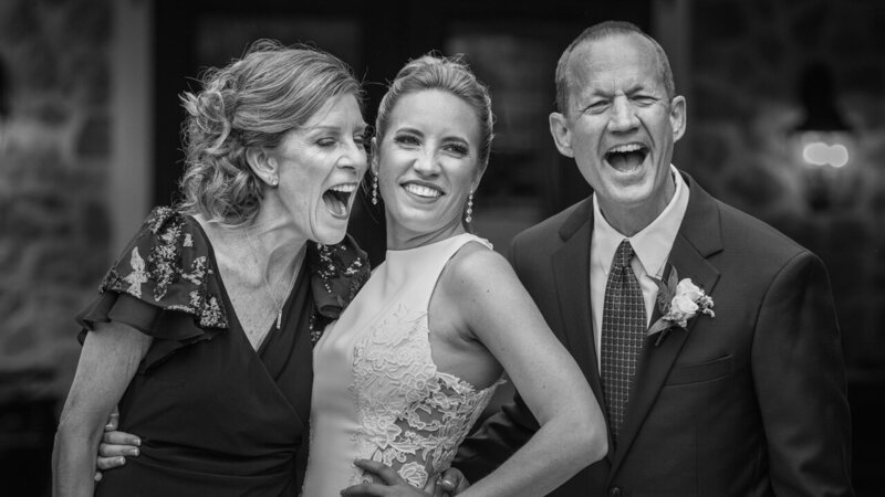 Bride laughing up a storm with her mom and dad on her wedding day, a candid and heartfelt moment captured in photojournalistic style.