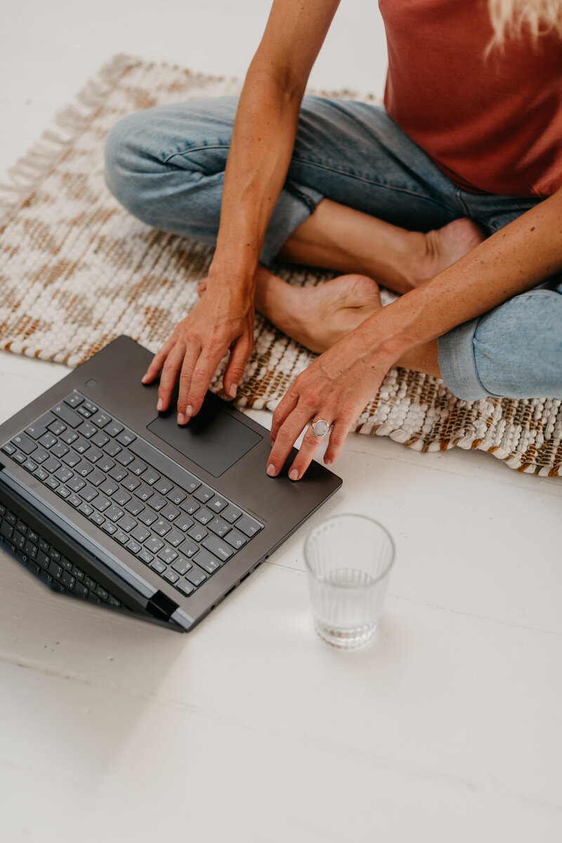 Woman sitting on floor typing on laptop
