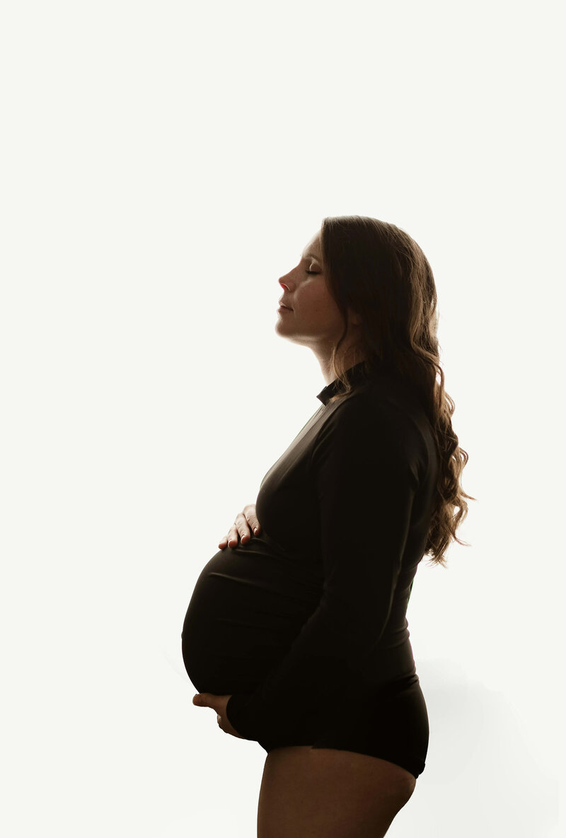 Side profile silhouette of pregnant woman in black bodysuit on white background