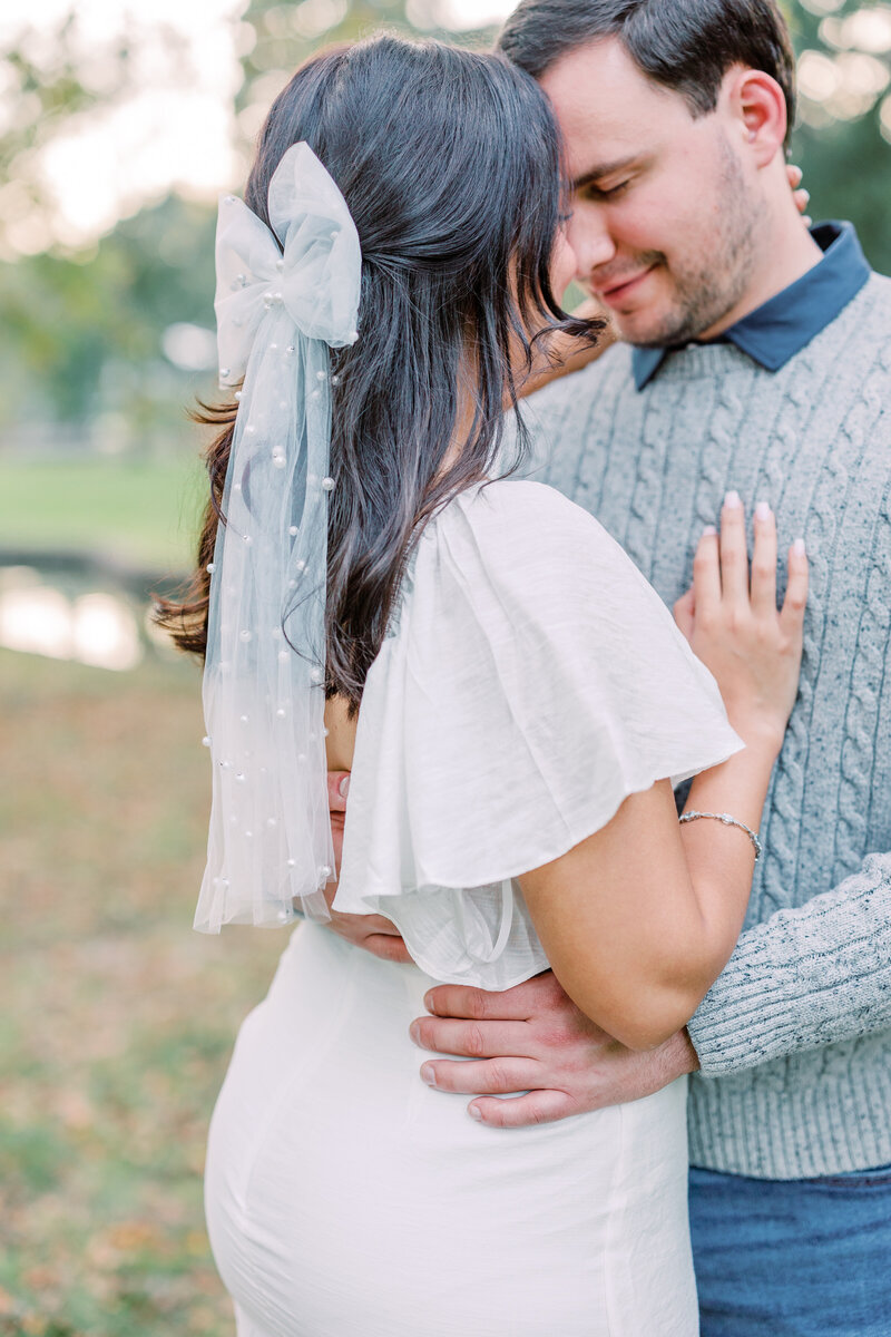 Woman in white dress and hairbow embracing man in grey sweater