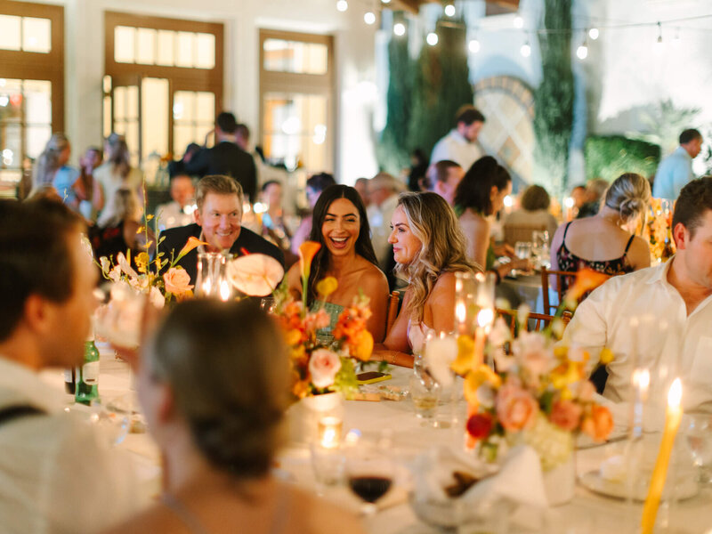 night time photography shot of wedding reception with people talking and smiling 