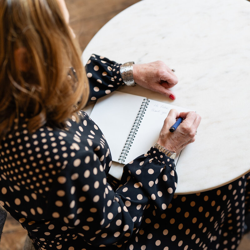 Woman sitting at a table and writing into a notebook
