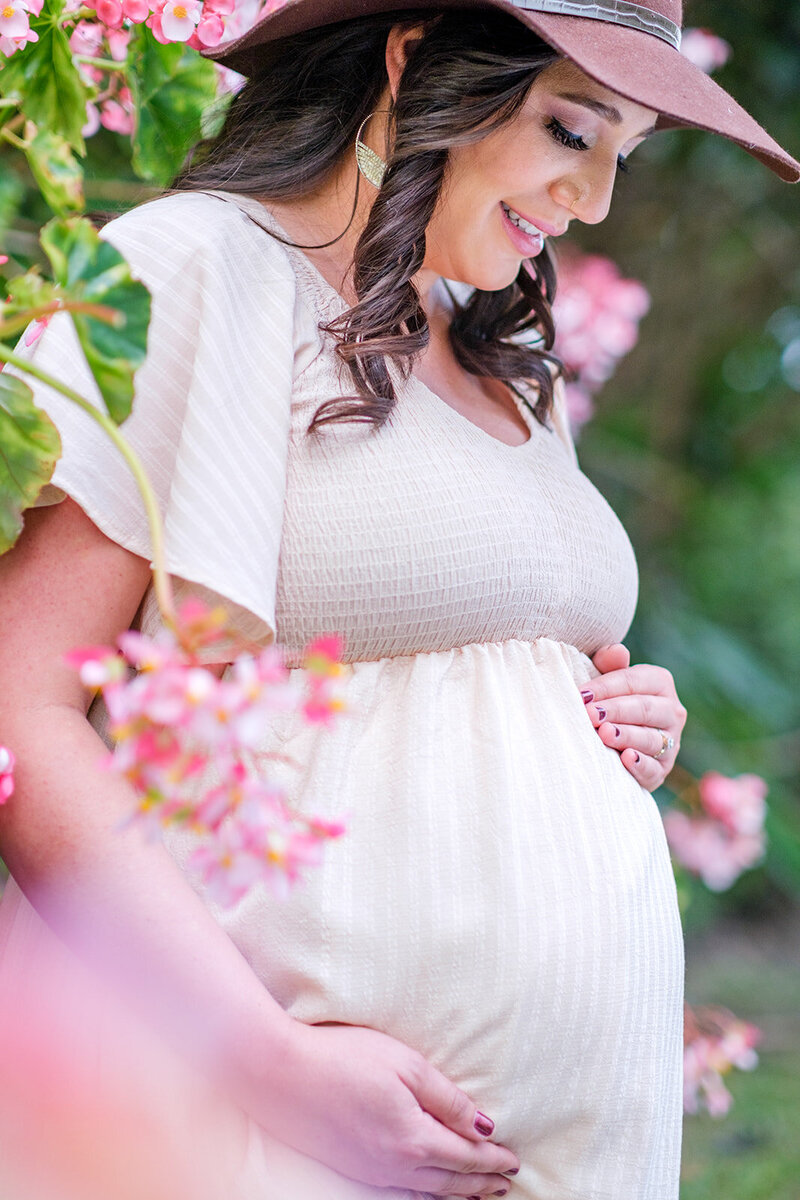 pregnant woman holding baby belly in pink dress with pink flowers