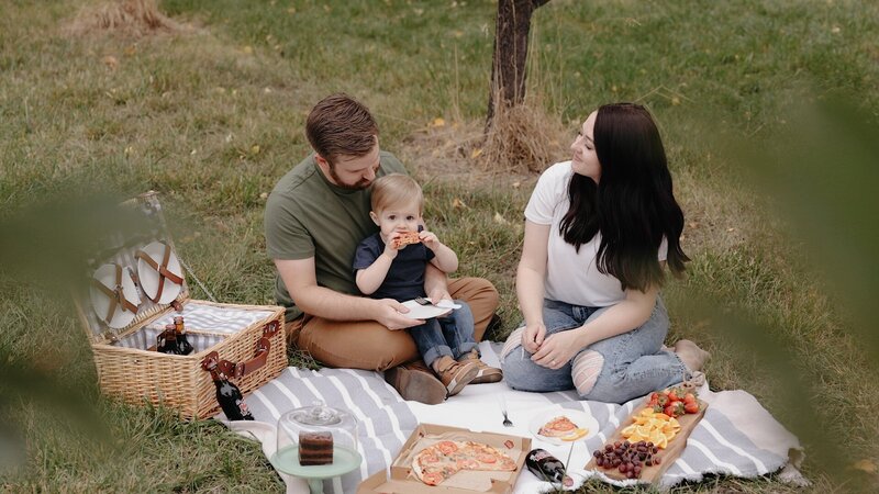 Young Family Having A Picnic In An Orchard