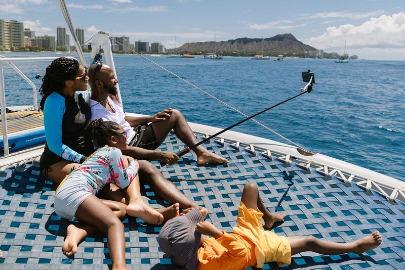 A family relaxes on a catamaran boat on Waikiki Beach.