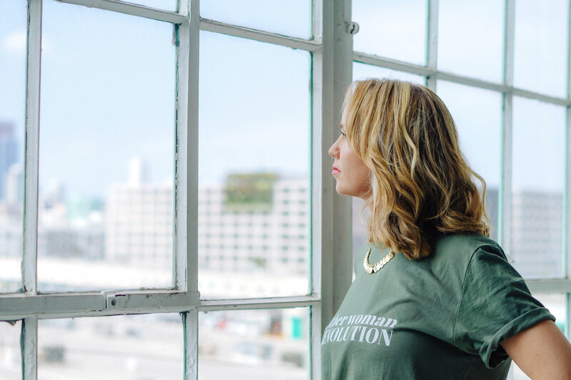 woman looking out through a window at a cityscape