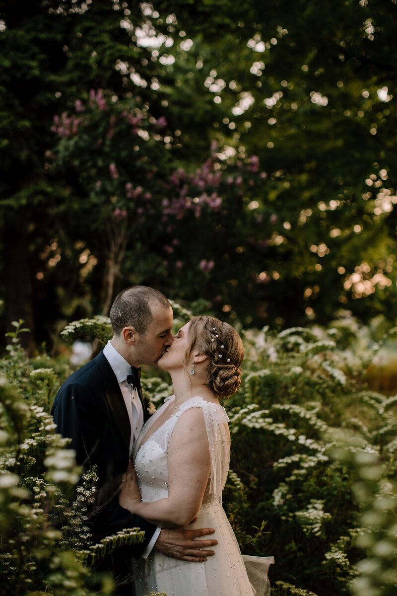 Bride and groom kissing in nature greenery