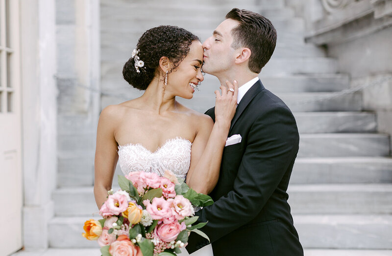 Interracial bride and groom kissing on their wedding day in the city